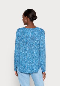 Blusa de manga longa em azul com um padrão floral disperso em branco e rosa. Tecido suave com decote redondo e ajuste descontraído.