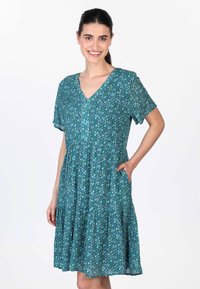 Kleid mit kurzen Ärmeln in Petrol mit floralem Muster, V-Ausschnitt, gerafftem Rock und seitlichen Taschen, aus leichtem Stoff gefertigt.