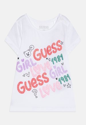 Weißes Kleinkind-T-Shirt mit buntem Glitzerschriftzug mit den Worten „Guess“, „Girl“, „Love“, „1981“ sowie kleinen Herzen, Sternen und einem Bären mit „Hi“-Sprechblase.