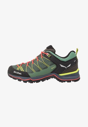 Chaussure de randonnée verte et noire avec une tige en maille texturée, des lacets rouges, des accents jaunes et une semelle robuste conçue pour l'accroche.