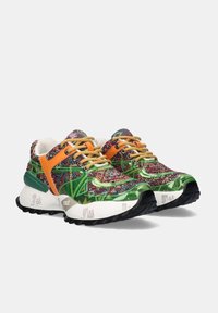 Zapatillas multicolores con acentos en verde, naranja y rojo, cordones beige, suelas acolchadas blancas y suelas texturizadas negras, mostradas sobre un fondo blanco.