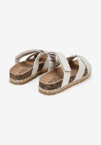 Sandali platform bianchi con cinghie incrociate, suola intermedia in sughero texturizzato e suola in gomma marrone e beige. Sottopiedi morbidi visibili.