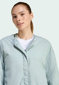 Svetlomodrá ľahká bunda s gombíkovou légou, voľný strih a mäkká textúra. Skvele sa hodí k bielej tričku s okrúhlym výstrihom pod ňou.