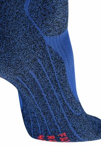 Calcetín azul y negro con patrones de punto texturizados y talón reforzado, con sutiles acentos rojos en la suela.