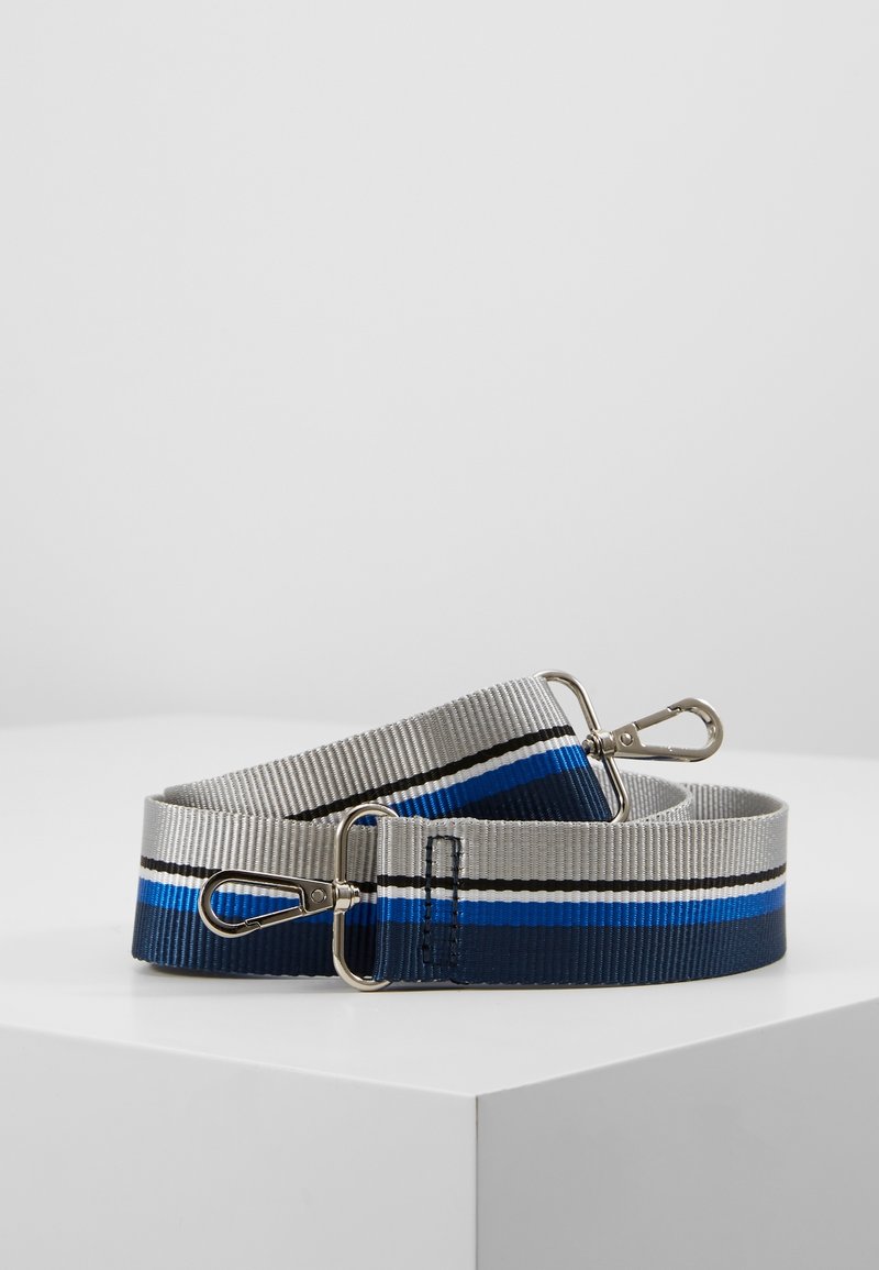 Cinturino per borsa in tessuto a righe grigio, nero, bianco, blu e navy con ganci a moschettone in metallo argentato su entrambe le estremità, arrotolato su una superficie bianca.