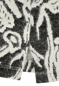 Schwarz-weißer gepunkteter Stoff mit weicher Textur, der abstrakte florale Designs zeigt. Gespaltene Saumdetail am unteren Rand.