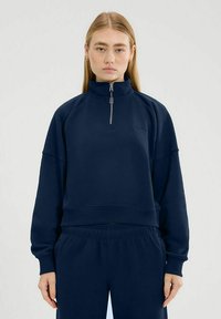 Maglione blu navy con colletto alto, chiusura a metà zip e vestibilità comoda. Realizzato in tessuto morbido, presenta polsini e orlo a costine.