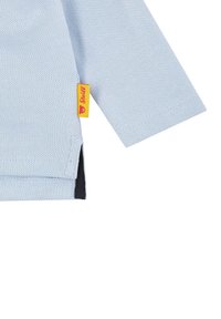 Lichtblauw langarmshirt van gestructureerde stof met een zwarte zoom. Bevat een gele 'Steiff' label aan de zijkant.