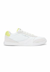 Baskets basses blanches avec accents en daim gris clair, languette de talon jaune et logo Tommy Hilfiger sur le côté.