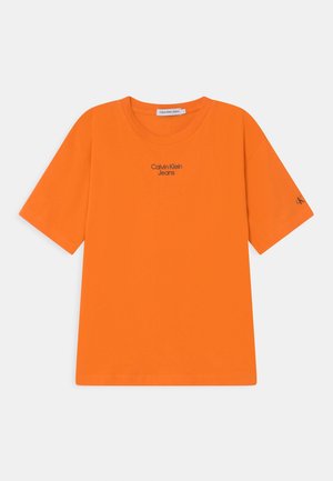 Orange T-shirt med korte ærmer, rund hals og "Calvin Klein Jeans" logo trykt i sort på forsiden. Glat bomuldsstof.