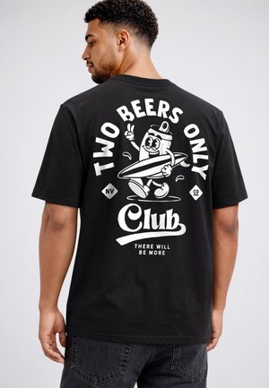 Mann trägt ein schwarzes T-Shirt mit weißem Aufdruck einer lächelnden Bierdose, die ein Surfbrett hält, und dem Text „Two Beers Only Club, There Will Be More.“