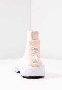 Roze stoffen enkelboot met een witte rubberen zool. Beschikt over 'TOMMY' branding aan de zijkant en een snug, gebreid ontwerp.