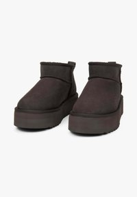 Suède enkellaarzen in donkergrijs, met een dikke plateauzool, een ronde neus en een gestikte naad langs de bovenrand.