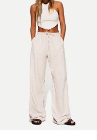 Ljusbeiga linnbyxor med en lös passform, med resårmidja och dragsko. I kombination med en strukturad vit crop top.