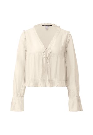 Cream-colored long-sleeve blouse with ruffled edges, front tie closures, and gathered cuffs, made from lightweight fabric.