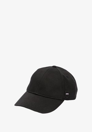 Casquette de baseball noire en tissu, avec une calotte arrondie, une visière incurvée et un petit écusson logo en forme de bouclier sur le côté.