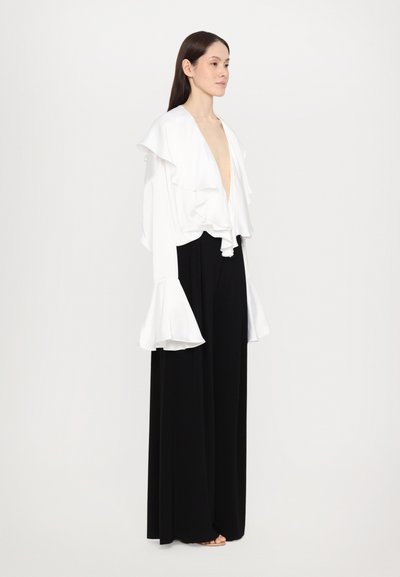 Witte gerimpelde blouse met een diepe V-hals en uitlopende mouwen, gecombineerd met zwarte wijde broek. Glad stof met een gestructureerde silhouet.
