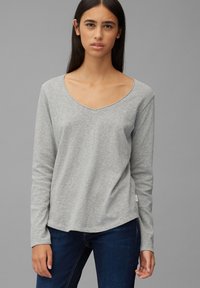 Grå langermet T-skjorte med V-hals, myk tekstur og rundkant. Brukt med mørke jeans, som viser et enkelt, uformelt design.