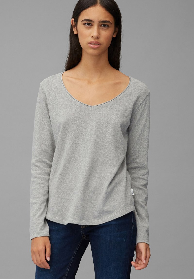 Grå langermet T-skjorte med V-hals, myk tekstur og rundkant. Brukt med mørke jeans, som viser et enkelt, uformelt design.