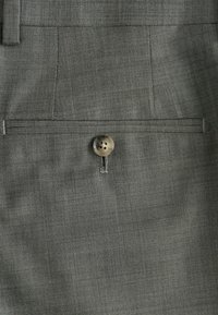 Gray houndstooth fabric pocket with a single beige button. Textured finish and clean lines for a sleek appearance.