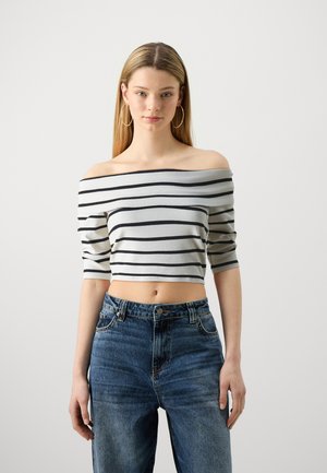 Top court à épaules dénudées avec des rayures grises et noires, doté de manches courtes. Associé à un jean en denim bleu taille haute.