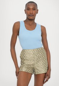 Top fără mâneci de culoare albastru deschis, cu textură ribbed și margini zimțate, asortat cu pantaloni scurți aurii strălucitori, cu un model floral și embellishments.