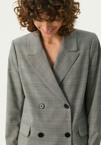 Grau karierter, doppelreiher Blazer mitrevers, zwei schwarzen Knöpfen und einem strukturierten Stoff. Verfügt über Seitentaschen und eine maßgeschneiderte Passform.