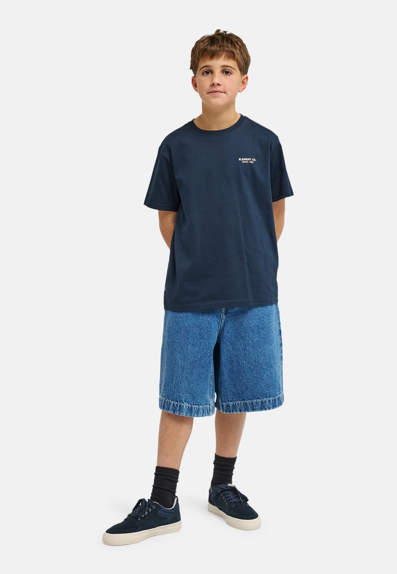 Marineblå bomulds-T-shirt med korte ærmer og rund hals, kombineret med lyseblå denimshorts, vist med afslappede sneakers.