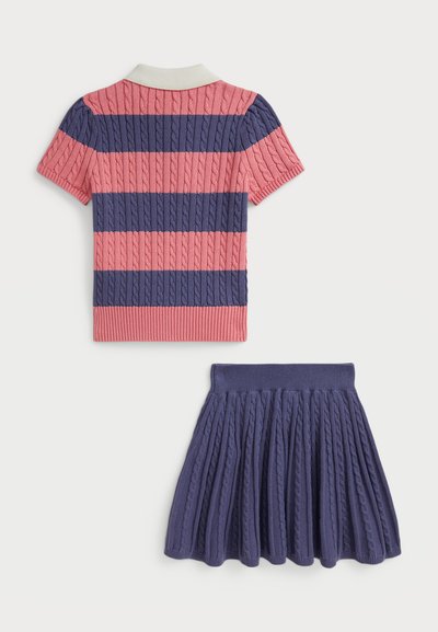 Polo à manches courtes rayé en rose et bleu marine avec une texture en tricot torsadé, associé à une jupe plissée bleu marine assortie dotée d'une taille côtelée.