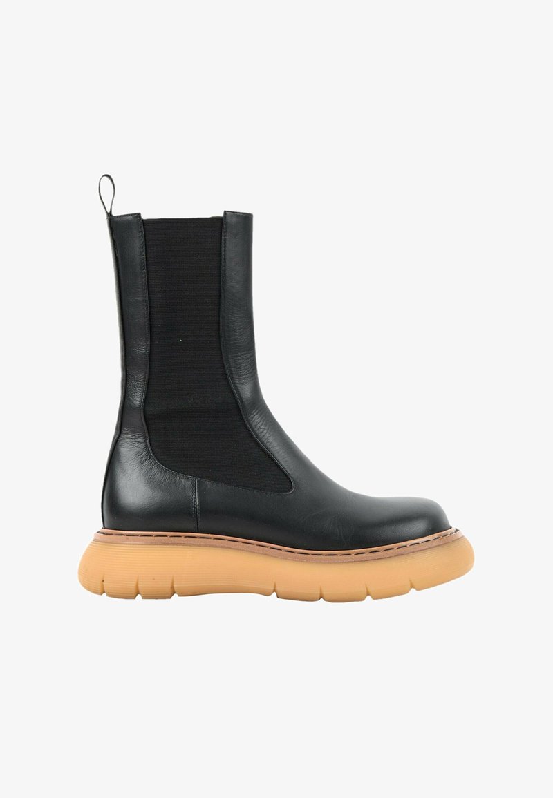 Bottine en cuir noir avec panneau latéral élastique et semelle épaisse en caoutchouc couleur fauve sur fond blanc.