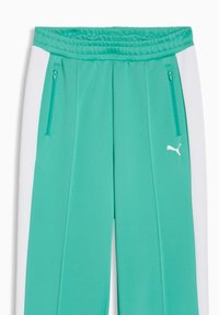 Τιρκουάζ φόρμα με ελαστική μέση, λευκές πλαϊνές ταινίες, δύο φερμουάρ σε μπροστινές τσέπες και μικρό λευκό λογότυπο Puma στο αριστερό μηρό.