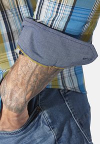 Blue and green plaid shirt with a denim cuff and contrasting yellow stitching, featuring a visible tattoo on the wrist.