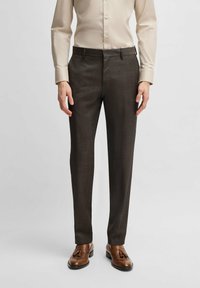 Dark brown tailored trousers with a subtle texture, straight leg design, and belt loops, paired with a light beige button-up shirt.