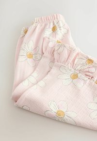 Pantalones de pijama rosas con estampados de margaritas blancas y amarillas, hechos de tela texturizada, con cintura elástica y bordes con volantes.