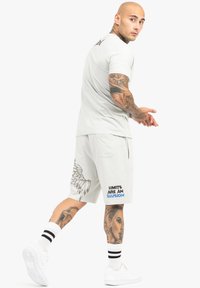 Heledane hallide spordirõivaste komplekt, mis koosneb lühikeste varrukatega t-särgist ja lühikestest pükstest. Pükstel on tiiva graafika ja sinine tekst "PIIRID ON PETTUS".