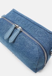 Denim kosmetikväska har en rektangulär form, blå färg, silverfärgad dragkedja med två blå läderdragare och präglad text på ytan.