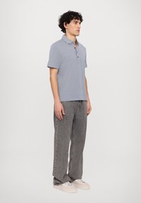 Light blue short-sleeve polo shirt with a collar, three-button placket, paired with gray straight-leg jeans and white sneakers.