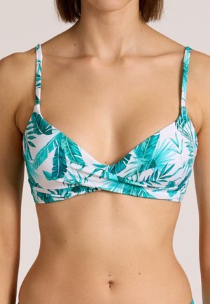 Frau trägt ein weißes Bikini-Oberteil mit grünem tropischem Blattmuster, dünnen Schulterriemen und einem leichten Twist-Detail vorne.