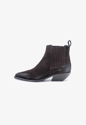 Stivale alla caviglia in suede marrone con punta affusolata, pannelli laterali elasticizzati e linguetta sul tallone. Presenta un tacco basso e impilato.