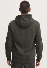 Felpa verde scuro con una texture morbida, tasca a marsupio e cappuccio regolabile con cordino. Design semplice e informale, senza decorazioni.