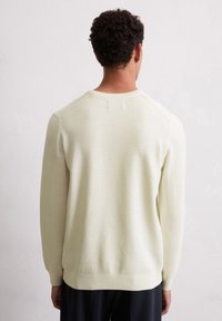Hellgelbes gestricktes Sweatshirt mit einem gerippten Rundhalsausschnitt und langen Ärmeln. Verfügt über ein strukturiertes Muster und dezente Schulternaht.
