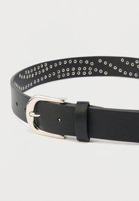 Μαύρη δερμάτινη ζώνη με ασημένια αγκράφα, διαθέτει πολλούς οπές κατά μήκος του ιμάντα για ρυθμιζόμενη εφαρμογή και επιπλέον διακοσμητική λεπτομέρεια.