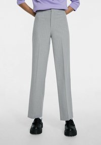 Šedé pruhované kalhoty s rovnými nohavicemi. Vyrobené z látky s hladkým povrchem, s vysokým pasem a elegantním siluetu.