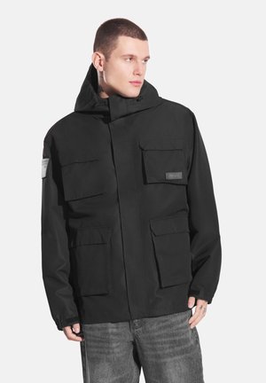 Czarna wodoodporna kurtka z kapturem, posiadająca cztery przednie kieszenie, regulowane mankiety oraz odznakę na rękawie. Miękka w dotyku, nowoczesny design.