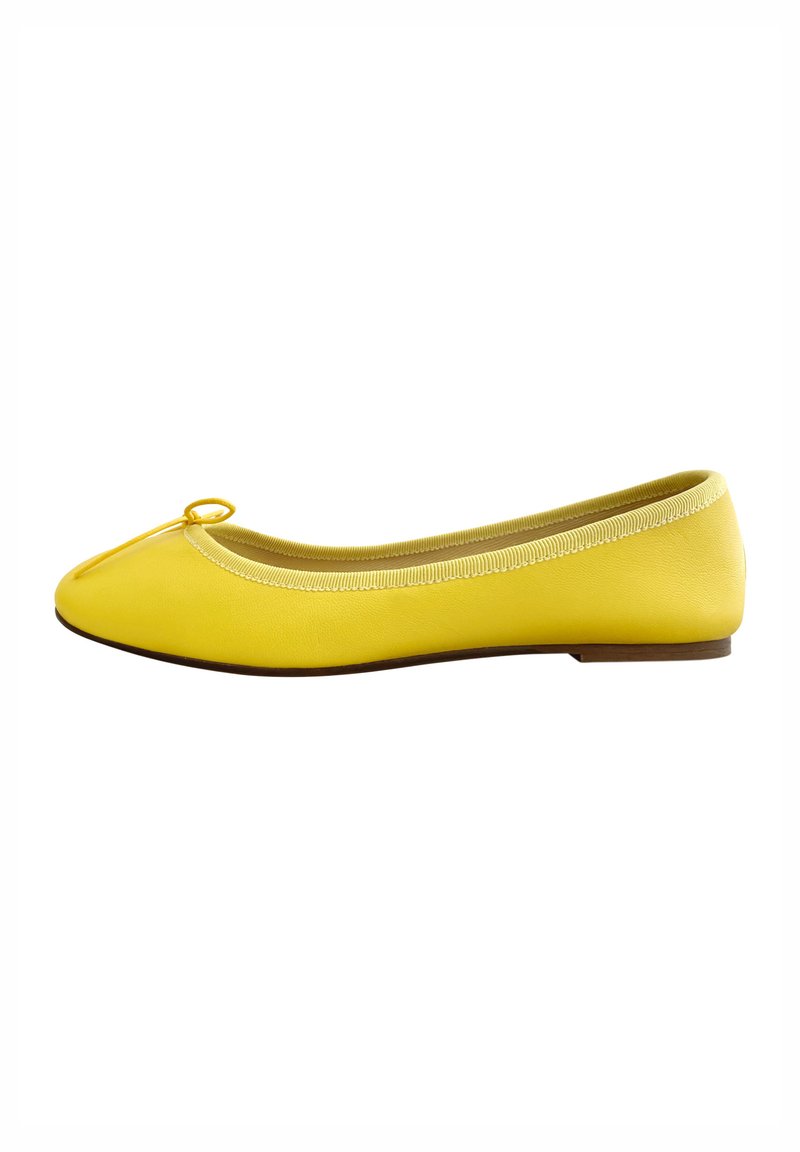 Ballerine gialle con punta arrotondata, in morbido materiale sintetico, con un piccolo fiocco decorativo sulla punta e una suola bassa marrone.