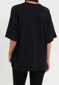 Black short-sleeve t-shirt made of soft cotton, featuring a relaxed fit and round neckline, with visible stitching and a straight hem.