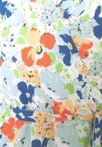 Blommönstrad tyg i ljusblått, med orange, röda, gröna och gula blommor. Strukturerad yta med en omslagsdesign.