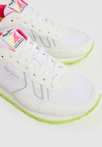 Witte sneakers met een textuurovervlak, neon groene zool en roze accenten op de tong. Voorzien van vetersluiting en logo-details.