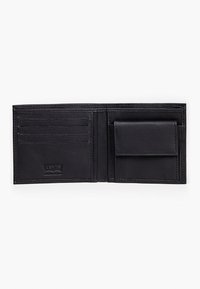 Svart läderplånbok med flera kortfack, ett centralt fack och en texturerad insida, med varumärkets logotyp präglad längst ner till höger.