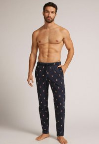 Pantalones de pijama azul marino con un patrón repetido de pequeñas figuras coloridas, cinturilla elástica, bolsillos laterales y un ajuste ceñido.